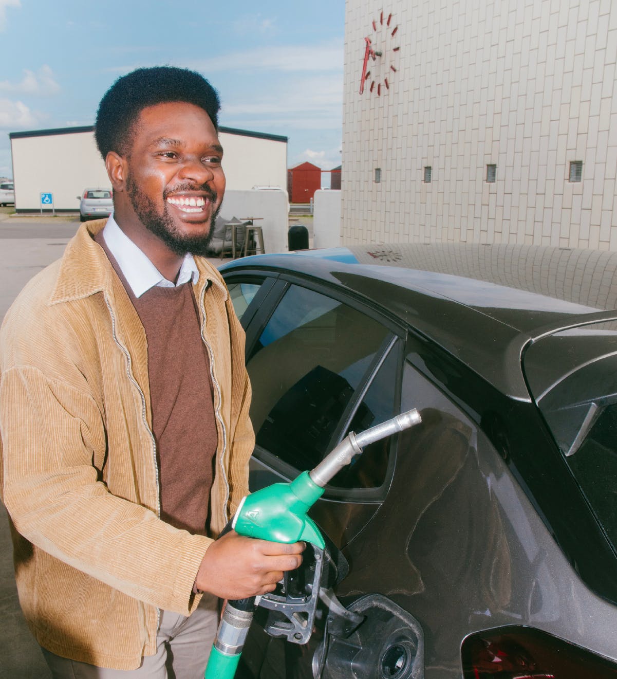 En glad medarbejder fylder benzin på sin bil